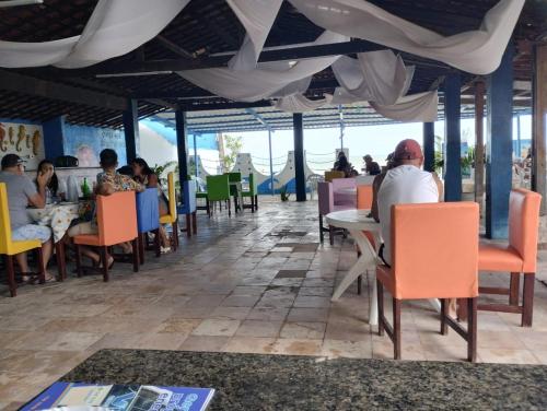 a restaurant with people sitting at tables and chairs at Pousada e Hotel Malibu in Paulista
