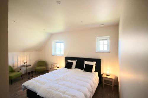 a bedroom with a large white bed with two windows at B&B 't Mjeels Pierke in Meerle