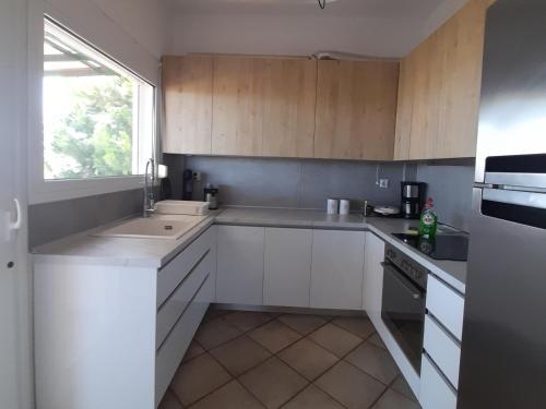 a kitchen with white cabinets and a sink and a window at Villa Aroma in Polykhrono