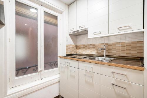 una cocina con armarios blancos y fregadero en apartamento en la puerta del sol, en Madrid
