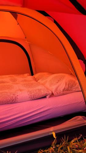 uma tenda laranja com uma cama em Haramsøy One Night Glamping- Island Life North- overnight stay in a tent set up in nature- Perfect to get to know Norwegian Friluftsliv- Enjoy a little glamorous adventure em Haram