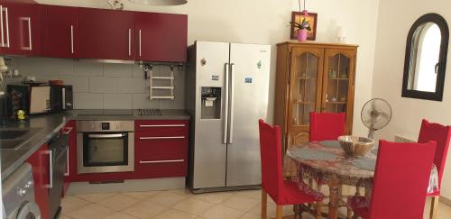 une cuisine avec des placards rouges et une table avec des chaises rouges dans l'établissement Très bel appartement,proche plage et centre ville., à Calvi