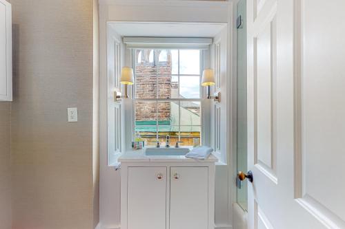 a bathroom with a sink and a window at Rainbow Row Pied-A-Terre in Charleston