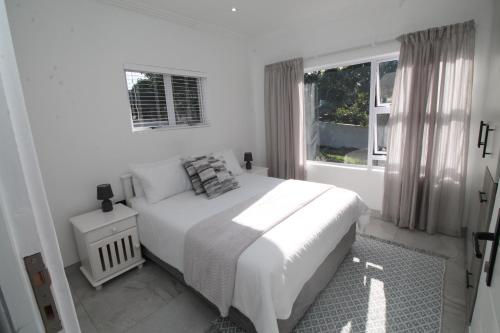 a white bedroom with a bed and a window at Villa Plaza in Shelly Beach
