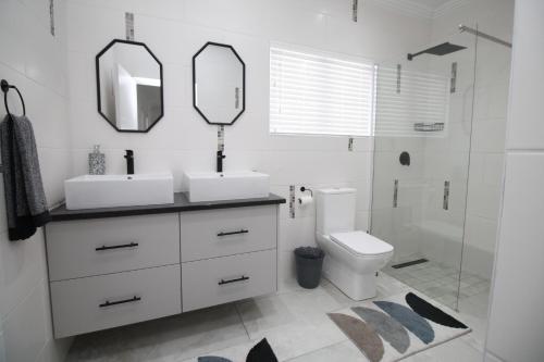 a bathroom with two sinks and a toilet and a shower at Villa Plaza in Shelly Beach