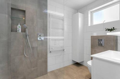 a bathroom with a shower and a toilet and a sink at Venture Vacation-Family Friendly Retreat-HOT TUB in Mosfellsbær