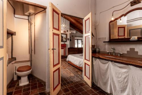 a bathroom with a toilet and a sink and a bed at Casa Scaparone in Alba