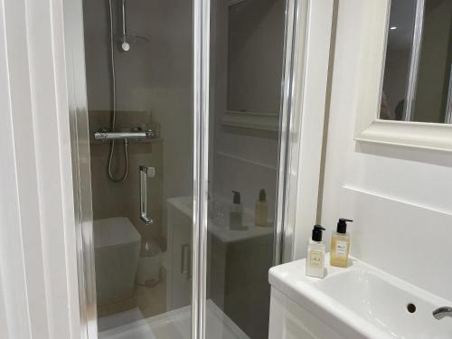a white bathroom with a shower and a sink at The Greig 1A in Wadhurst