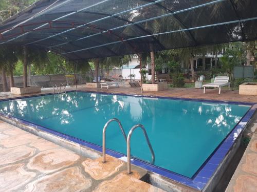 a large swimming pool with an umbrella over it at New Sunrise Hotel in Batticaloa