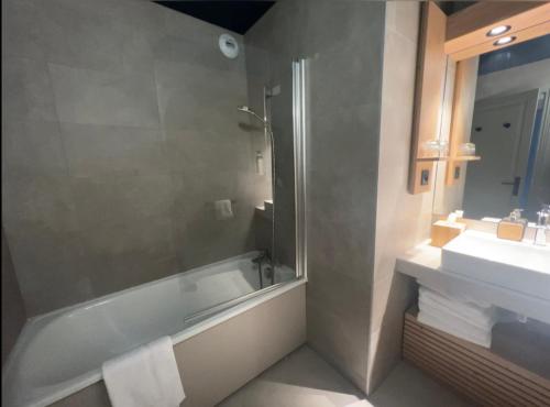 a bathroom with a shower and a tub and a sink at La Cachette, Friendly Hotel & Spa in Arc 1600