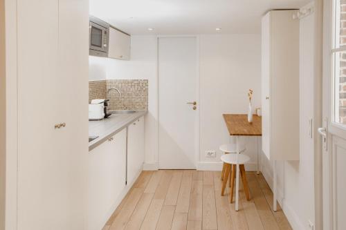 een keuken met witte kasten en een houten vloer bij Magnifique maisonnette sur cour intérieur proche des quais de la seine in Parijs