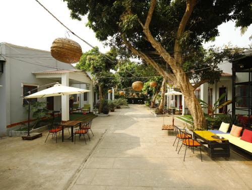 a patio with tables and chairs and a tree at Eden House & Coffee Con Dao in Con Dao