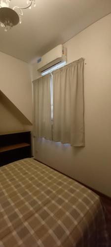 1 dormitorio con cama y ventana con cortina en PH Don Salvador en Rosario