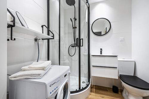 a white bathroom with a shower and a washing machine at Apartament Octopus Sopot Kamienny Potok in Sopot