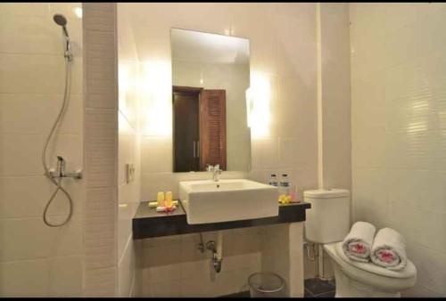 a bathroom with a sink and a toilet and a mirror at Dalia Budget Hotel in Senggigi