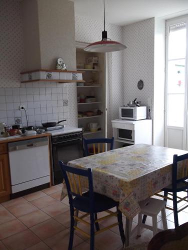 eine Küche mit einem Tisch und Stühlen sowie eine Küche mit einer Mikrowelle in der Unterkunft Gîte -Belle Maison dans une ancienne école-Tarif réduit hors WE ! in Chanzeaux