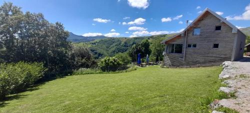 a house with a grassy yard next to a building at Holiday home Vila Bjelašnica in Bjelašnica