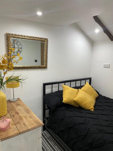 um quarto com uma cama com almofadas amarelas e um espelho em Egos em Castle Donington