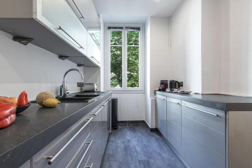d'une cuisine avec des placards gris, un évier et une fenêtre. dans l'établissement FEEL HOME - FOCH 28, à Nice
