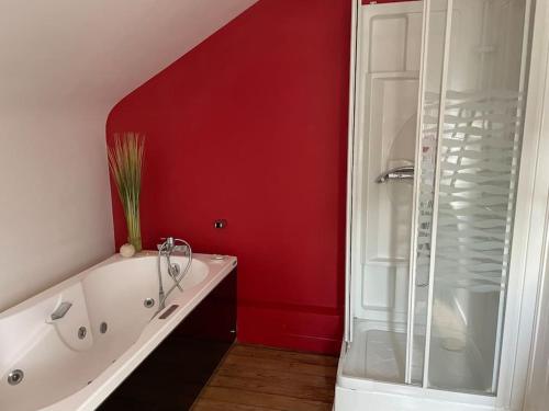 La salle de bains rouge est pourvue d'une baignoire et d'une douche. dans l'établissement Maison centre ville à Bergerac, à Bergerac