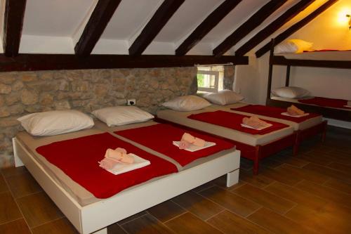 two beds in a room with red sheets and pillows at Kuća za odmor Krasnica in Novi Vinodolski