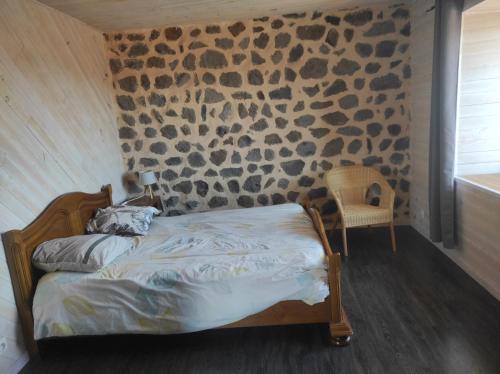 Gite La Tourterelle في Le Brignon: غرفة نوم بسرير وجدار حجري