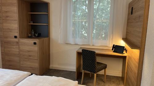 a bedroom with a desk with a chair and a window at Hotel-Cocco-Bello in der Villa Foret in Ludwigsburg