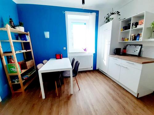a kitchen with a white table and a blue wall at Große Altbauwohnung auf dem Land in Kallham
