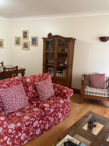 a living room with a red couch and a book shelf at Tia Rita House in Figueira da Foz