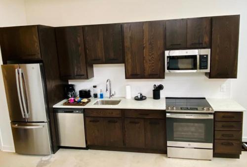 a kitchen with wooden cabinets and a stainless steel refrigerator at Cozy Apt Across From Ballpark Busch Stadium in Saint Louis