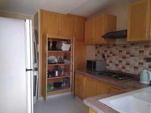 a kitchen with wooden cabinets and a stove top oven at Bel appartement plein centre avec double terrasse in Oujda