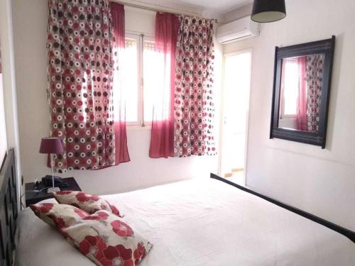 a bedroom with a bed with red curtains and a window at Bel appartement plein centre avec double terrasse in Oujda
