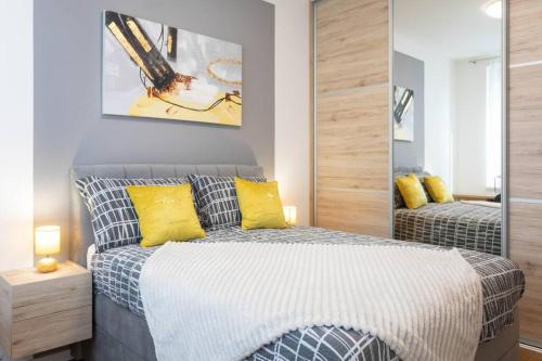 een slaapkamer met een bed met gele kussens en een spiegel bij Lux oasis with private parking in Zagreb