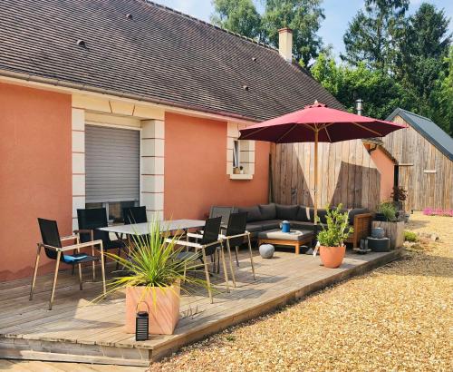 a patio with a table and chairs and an umbrella at Bras de Mer in Cérans-Foulletourte