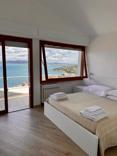 a bedroom with two beds and a view of the ocean at Tuscan Sunrise in Porto Santo Stefano