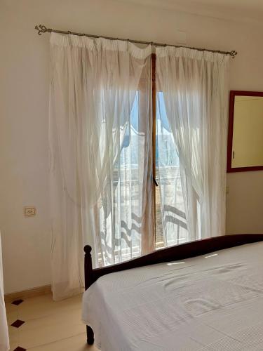 1 dormitorio con 1 cama y una ventana con cortinas blancas en Casa CaboMar en Torrevieja