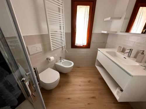 a white bathroom with a toilet and a sink at Tuscan Sunrise in Porto Santo Stefano
