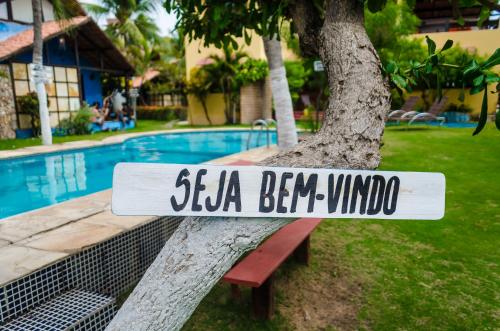 un cartel sentado en un banco junto a una piscina en Pousada Refúgio do Manatí, en Canoa Quebrada