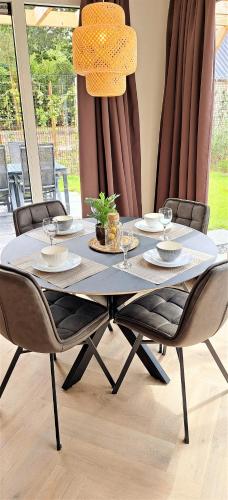 a dining room table with chairs and a chandelier at Luxe Natuurhuis Veluwe Home 'De Bosvogel' in Ermelo