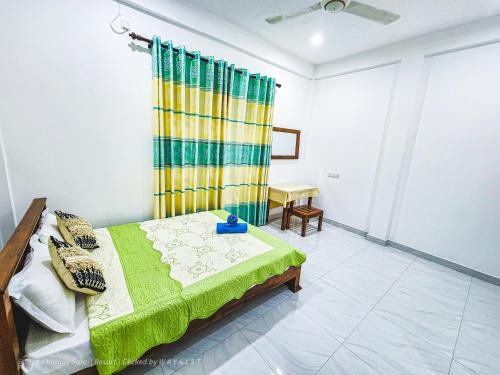 a bedroom with a bed with a green and yellow curtain at Green Village Safari Resort in Udawalawe