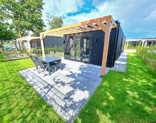 een zwarte schuur met een tafel en stoelen in een tuin bij Veluwe Home 'De Bosvogel' luxe natuurhuis in Ermelo