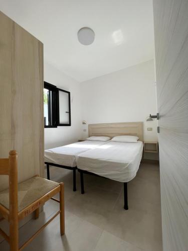 una camera con due letti e una sedia e una finestra di Villaggio Almar a Vieste