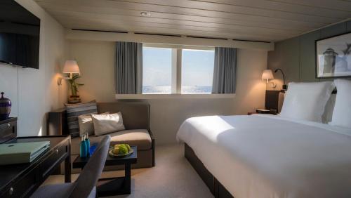 Pokój hotelowy z łóżkiem, biurkiem i kanapą w obiekcie Four Seasons Explorer Palau - Cruising Resort w mieście Koror