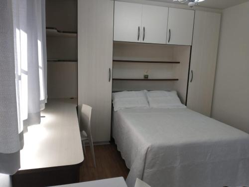 Dormitorio pequeño con cama blanca y armarios blancos en Residencial Vitor Studio 5, en São José dos Pinhais