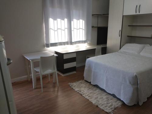 1 dormitorio con cama, escritorio y mesa en Residencial Vitor Studio 5 en São José dos Pinhais