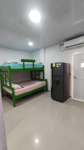 コベニャスにあるLa Roca Coveñas Apartamentosの緑色の二段ベッド、小型冷蔵庫が備わる客室です。