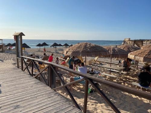 a group of people on a beach with straw umbrellas at Amazing Sea View Beach House in Lourinhã