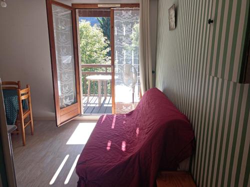 a bedroom with a bed with a purple comforter and a balcony at Appartement entre thermes et montagne in Luchon