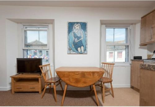 uma cozinha com uma mesa e cadeiras e uma televisão em bEaUtiFUL and Bright !! Town/Harbour apartment #2 em Penzance