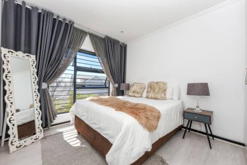 ein Schlafzimmer mit einem großen Bett und einem großen Fenster in der Unterkunft Urban Oasis - 3 Bedroom Home in Sandton